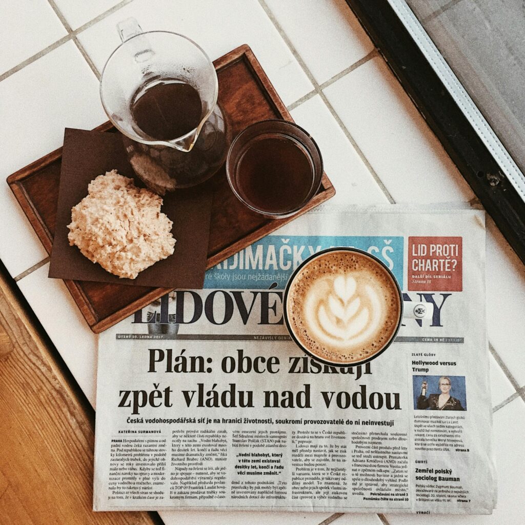 Overhead view of a cozy coffee setup with a newspaper in a Prague café, perfect for relaxed morning vibes.