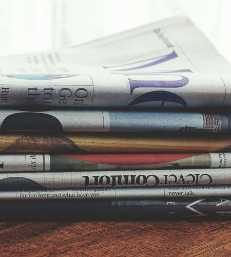 A stack of folded newspapers placed on a wooden table, symbolizing news and information.